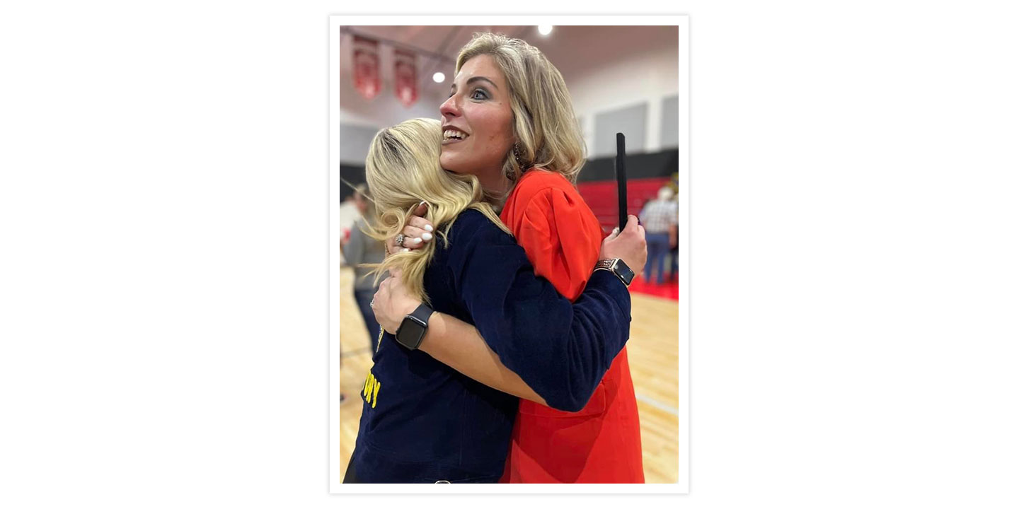 A woman with blonde hair smiling and hugging an FFA member with Blonde hair.